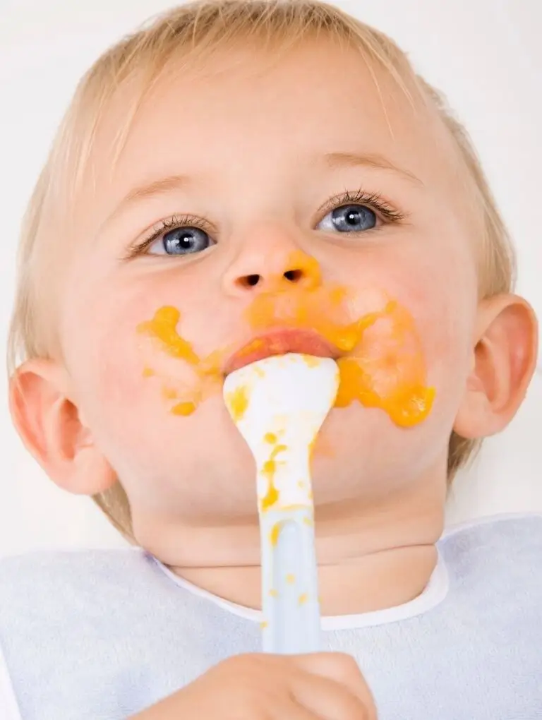 Baby mit verschmiertem Mund macht erste eigene Esserfahrungen