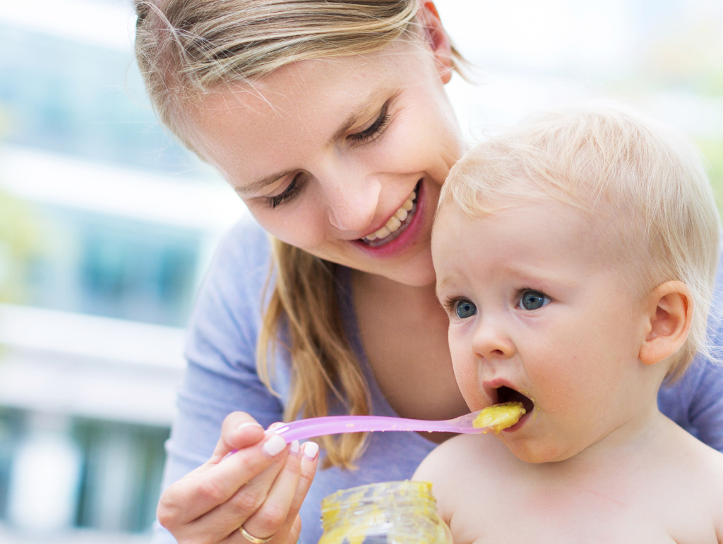 Mutter füttert Baby mit Beikost – sicherer Start in die Beikostzeit