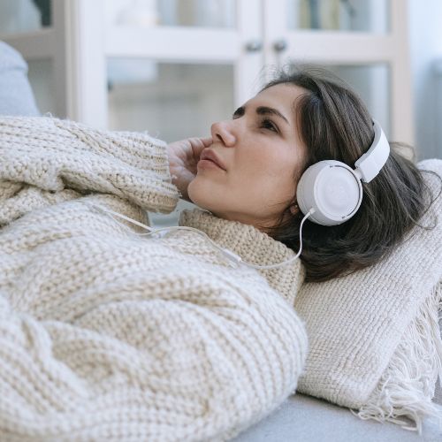 Frau hört eine Audiodatei aus dem Kurs Progressive Muskelentspannung