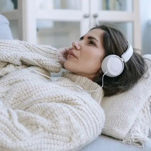Frau hört eine Audiodatei aus dem Kurs Progressive Muskelentspannung