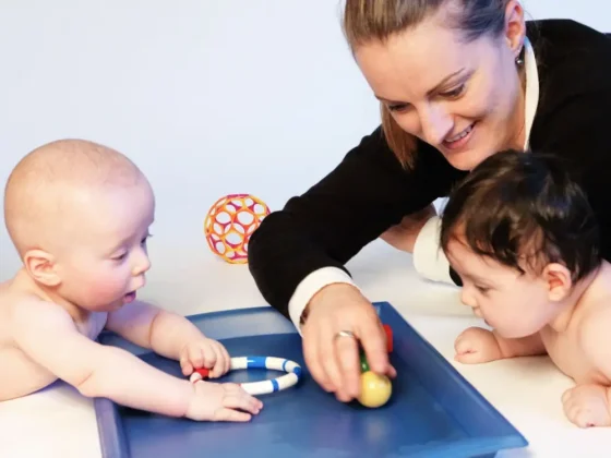2 Babys mit Spielzeug und Mama in einem PEKiP Kurs
